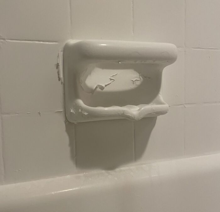 Peeling paint on a worn soap holder in a bathroom showing infuriating landlord neglect and landlord specials.
