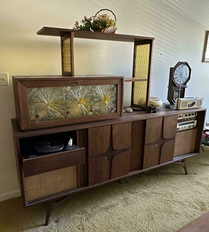 Mid-century designs wooden furniture with vintage glass panel, record player, and retro clock in living room setting.