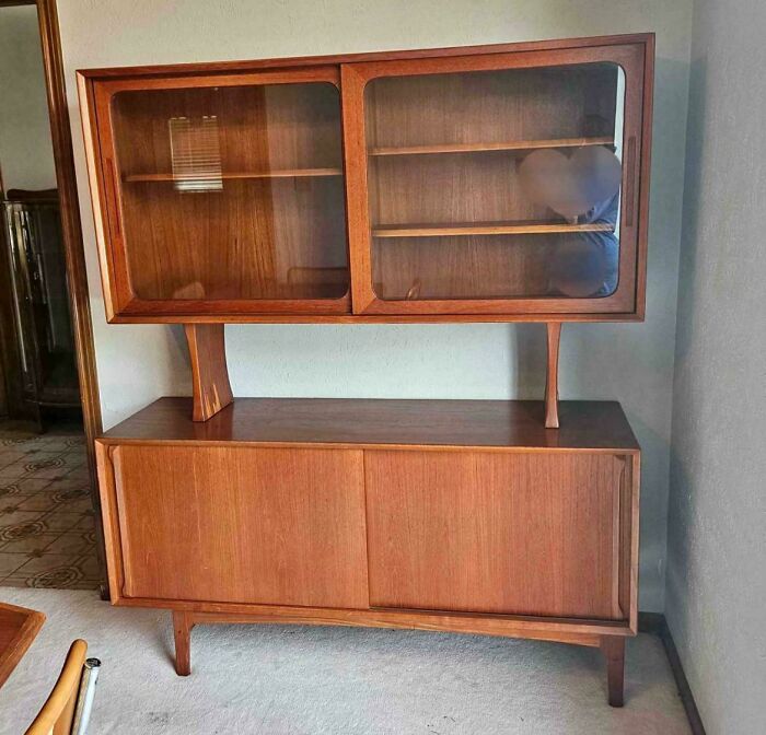 Mid-century wooden cabinet with glass doors and sliding panels showcasing classic vintage charm in a living room setting.