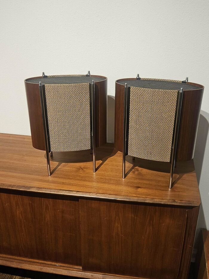 Pair of mid-century design wooden speakers with vintage woven fabric on a wooden cabinet, showcasing effortless vintage charm.