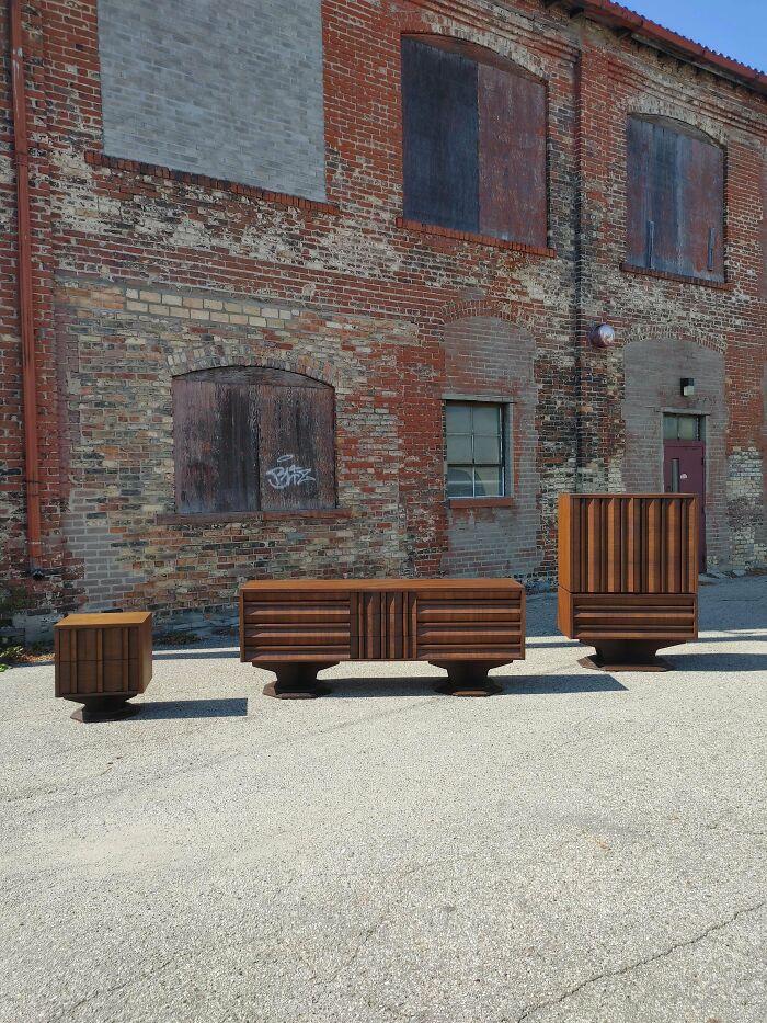 Mid-century designs featuring vintage wooden furniture pieces arranged outdoors against a rustic brick wall.