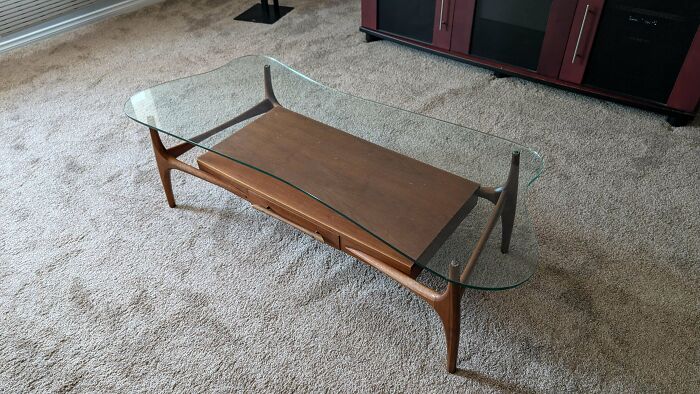Mid-century design glass and wood coffee table with vintage charm on beige carpet in modern living room.
