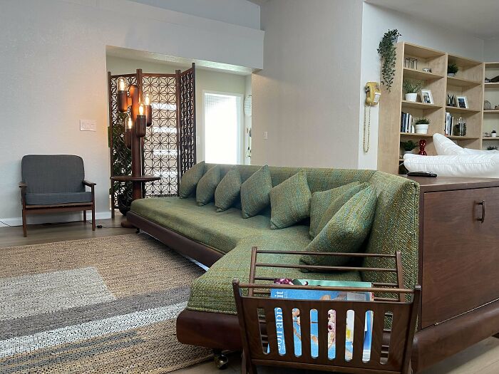 Mid-century living room with vintage green sofa, wooden shelving, and retro decorative accents radiating effortless charm.