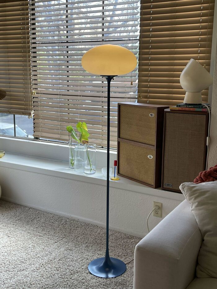 Mid-century design floor lamp with vintage speakers and minimalist decor by a window with blinds.