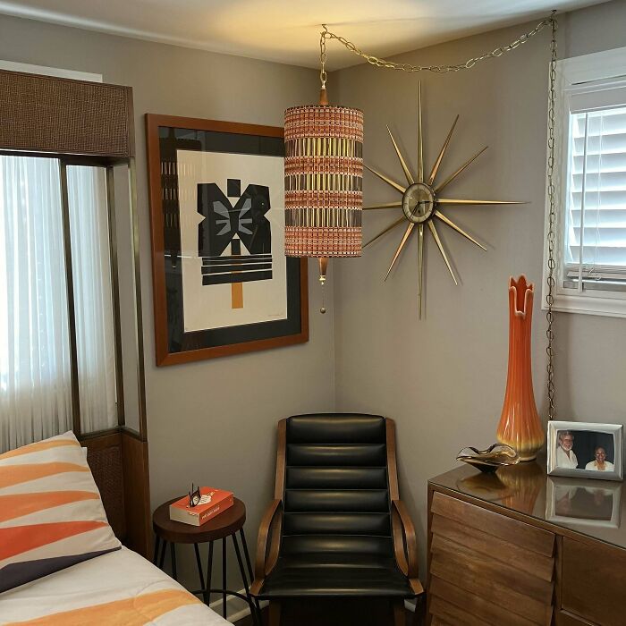 Mid-century design vintage bedroom corner with black leather chair, geometric art, hanging lamp, and starburst clock.