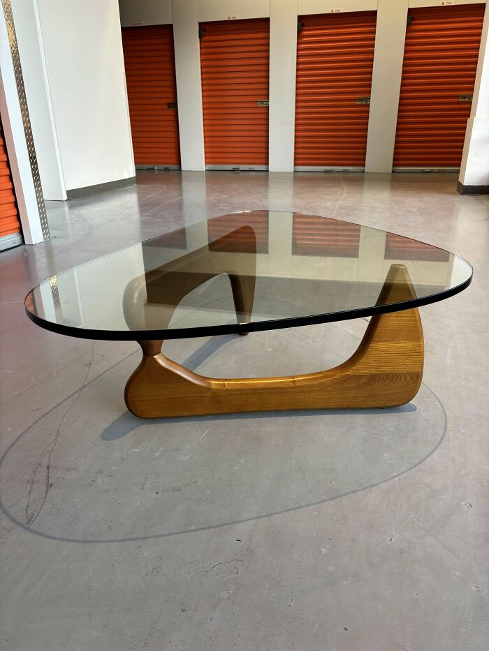 Mid-century design coffee table with sculptural wooden base and curved glass top showcasing vintage charm.