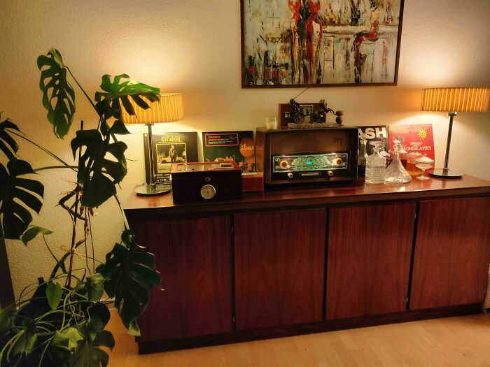 Mid-century vintage design featuring wooden sideboard, retro radio, vinyl records, warm lighting, and decorative glassware.