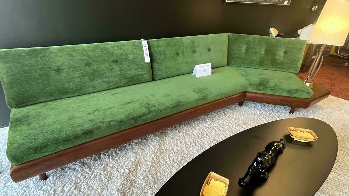 Mid-century designs featuring a green velvet vintage sofa with wooden frame and a black coffee table on white rug.