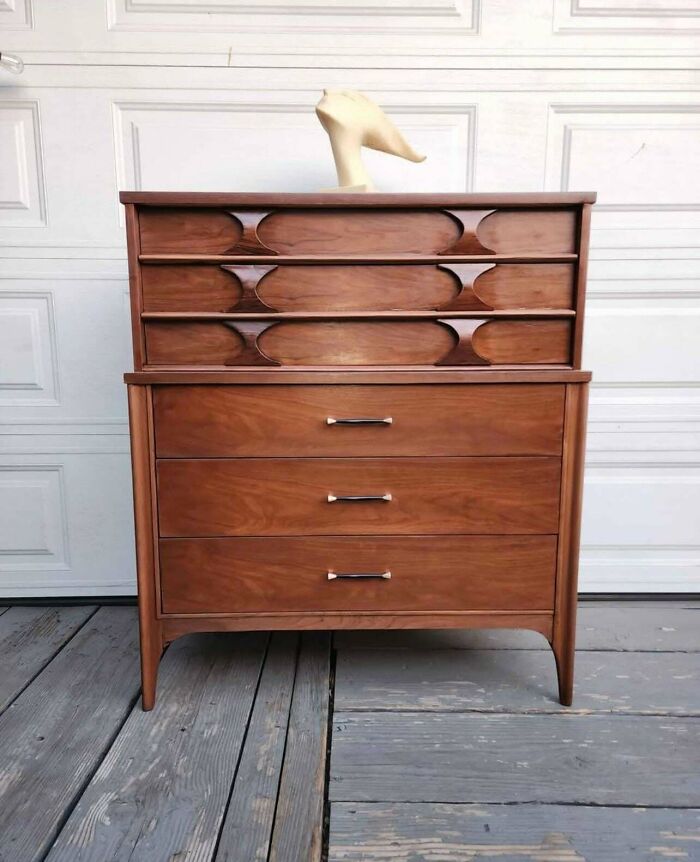 Mid-century wooden dresser with vintage charm, featuring clean lines and unique drawer designs on a wooden deck.