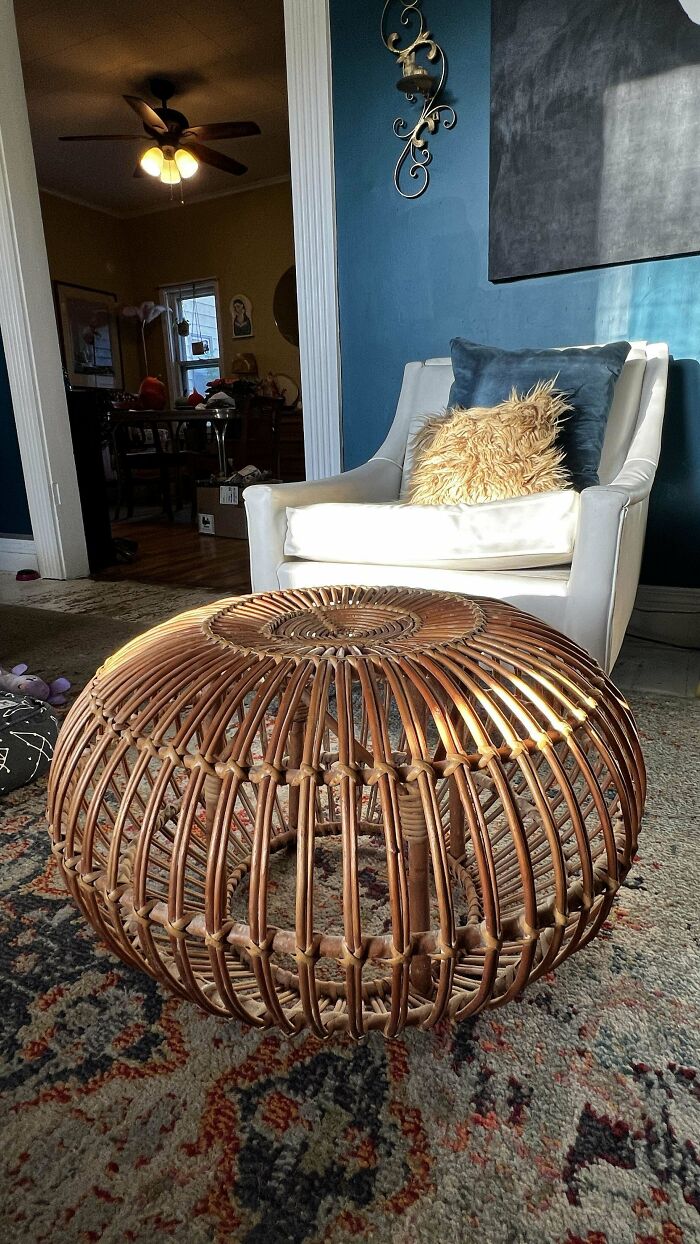 Rattan mid-century design coffee table in a living room with vintage mid-century chair and textured pillows.