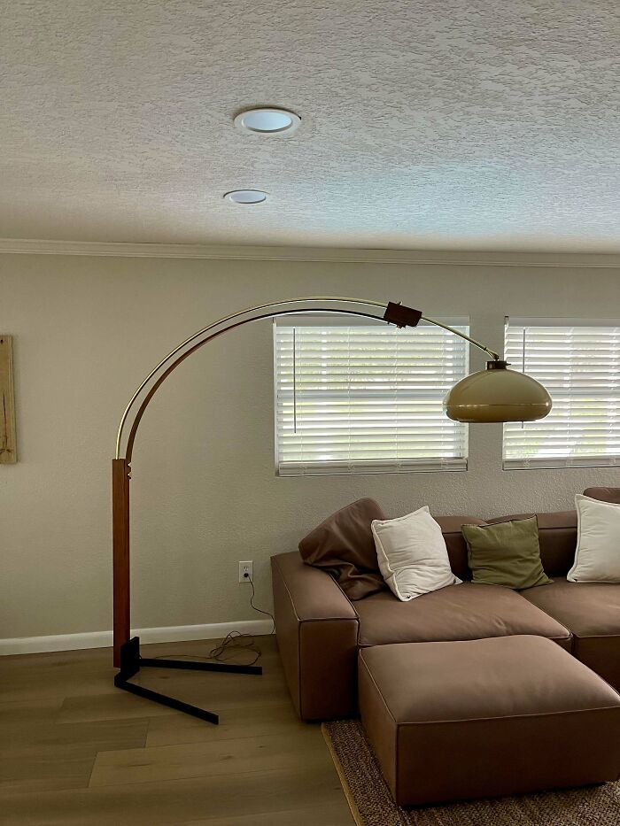Mid-century design living room with a brown leather sectional, vintage arc floor lamp, and minimalist decor.