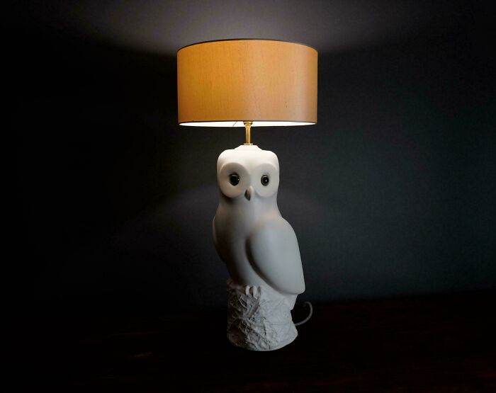 Mid-century lamp with owl design and beige shade, showcasing vintage charm and effortless retro style in a dark setting.