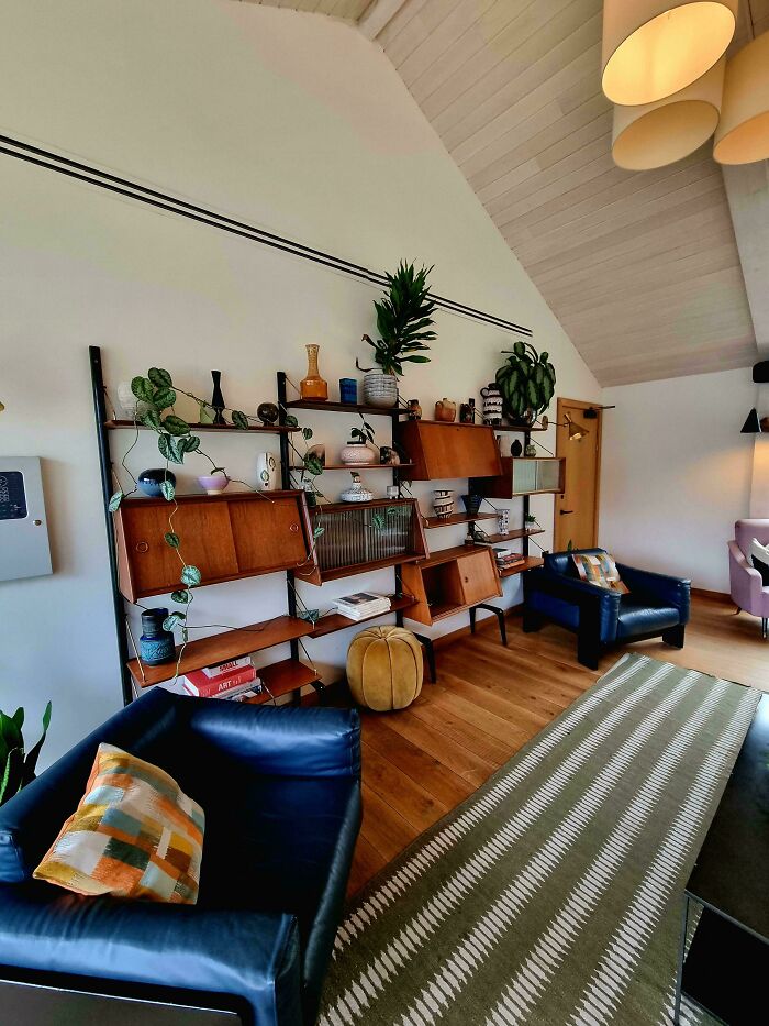 Mid-century designs in a cozy living room with leather chairs, wood flooring, patterned rug, and vintage shelving decor.