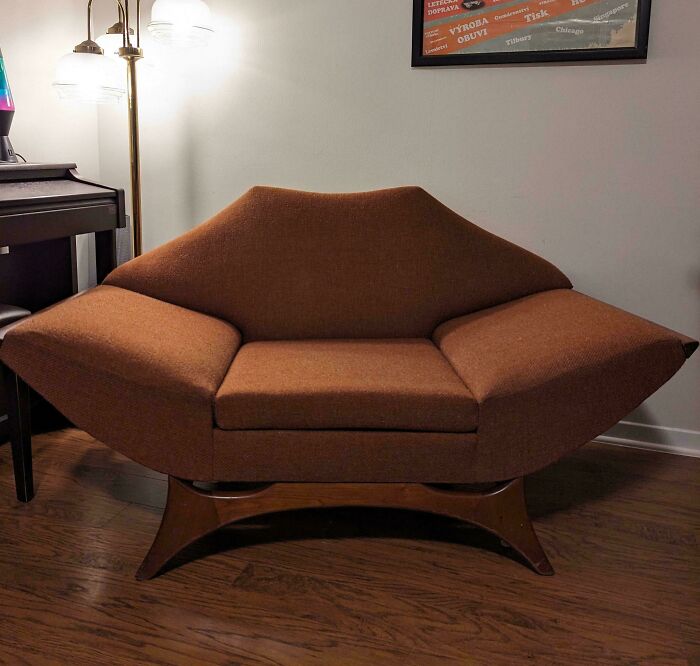 Mid-century modern sofa with vintage charm in brown upholstery and wooden base, styled in a cozy retro living room setting.