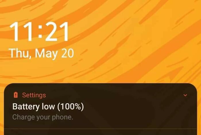 Phone screen showing a tech fail with a "Battery low (100%)" message on an orange background.