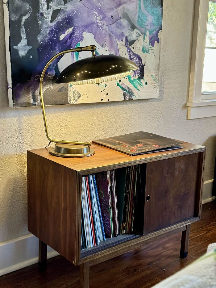 Mid-century designs featuring a vintage wooden cabinet with records and a brass desk lamp in a cozy room.