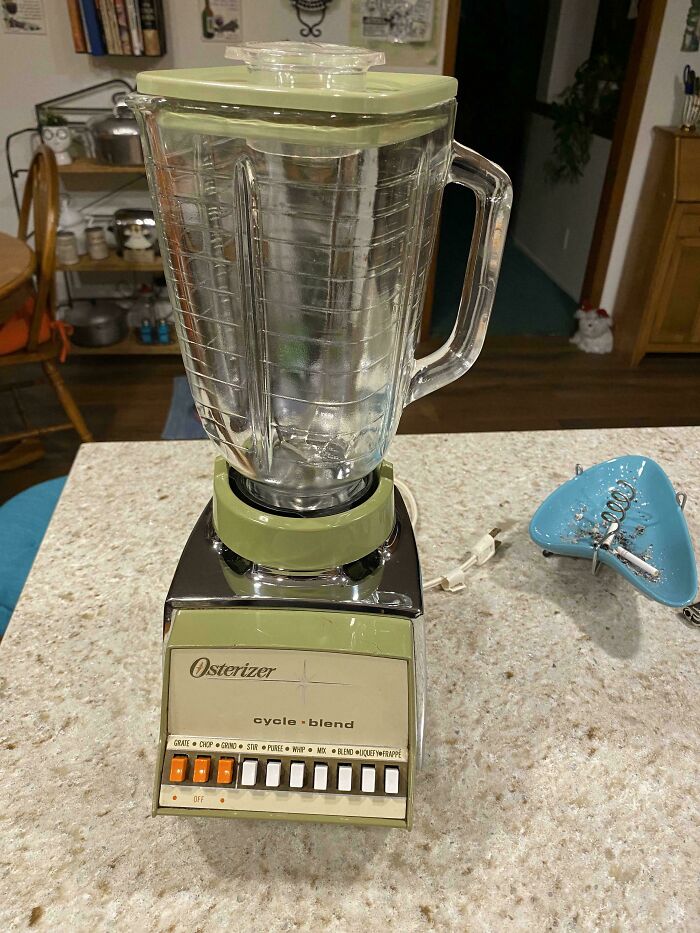 Vintage mid-century blender with glass jar and olive green accents on a kitchen countertop showing effortless vintage charm.