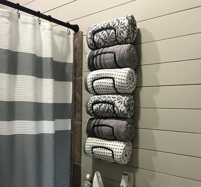 Stacked rolled towels held by wall rack in bathroom, showcasing easy home upgrades for weekend projects.