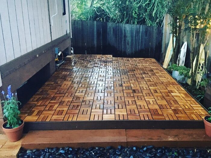 Wooden tile patio deck upgrade in backyard surrounded by fence and plants for easy weekend home improvement.