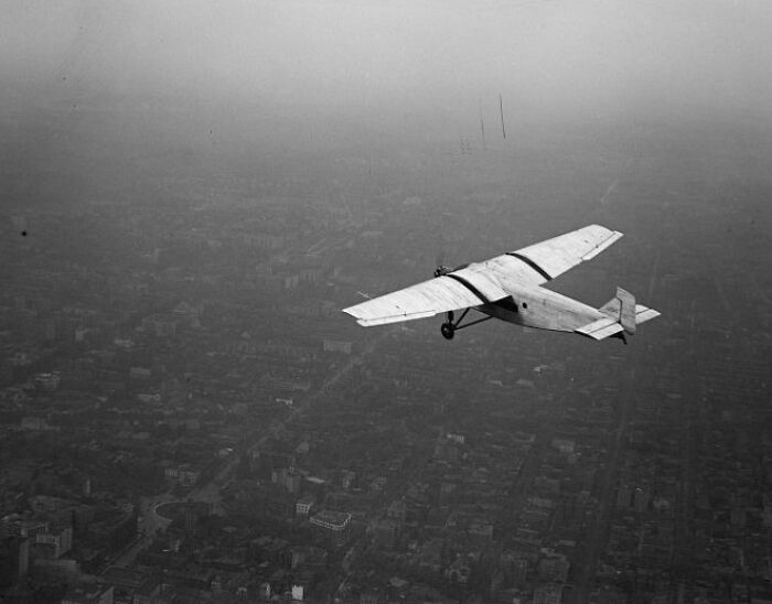 Vintage plane flying over a cityscape, showcasing early aviation and the magic of historic aircraft in flight.