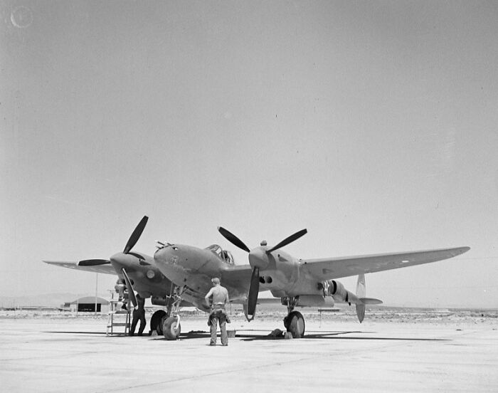 Vintage photo of a military plane on runway with crew inspecting and performing maintenance, capturing the magic of aviation.
