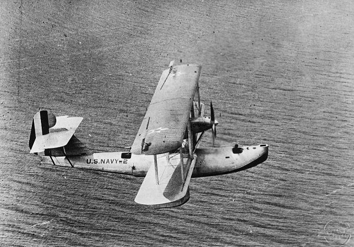 Vintage black and white photo of a U.S. Navy seaplane flying over the ocean, showcasing classic aviation history and planes.