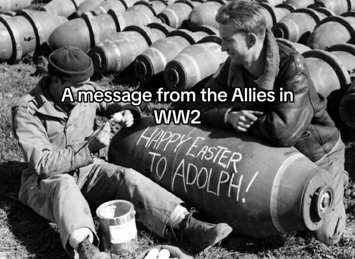 Black and white WWII photo showing soldiers writing a message on a b**b, capturing monumental life moments frozen in time.