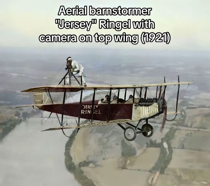 Aerial barnstormer Jersey Ringel with camera on top wing of vintage plane capturing monumental life moments in 1921.