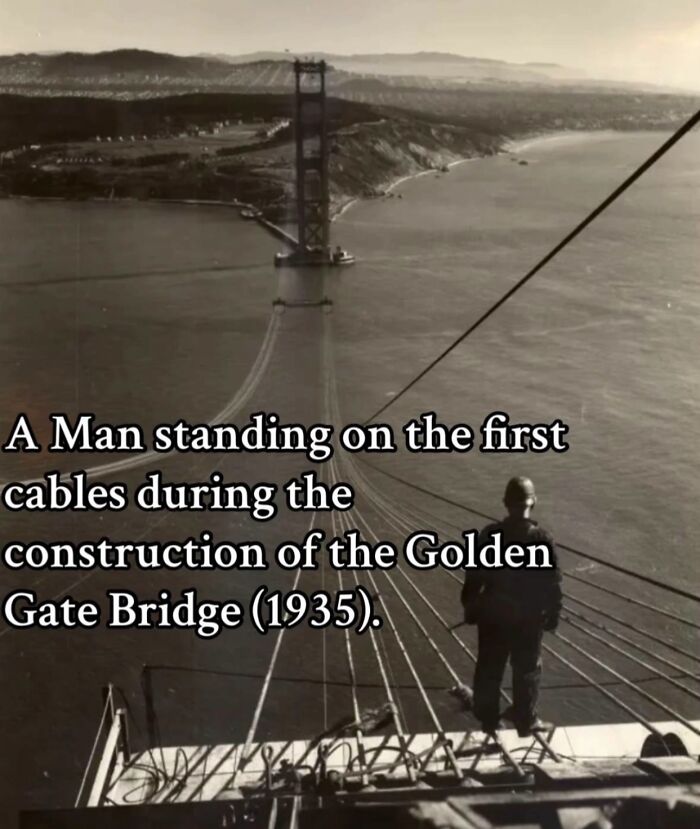 A man standing on early cables during the monumental construction of the Golden Gate Bridge, a historical life moment frozen in time.
