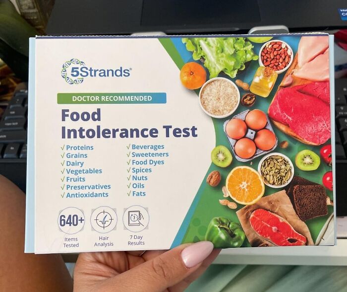 Hand holding 5Strands Food Intolerance Test kit featuring proteins, grains, dairy, fruits, and vegetables to identify intolerances.