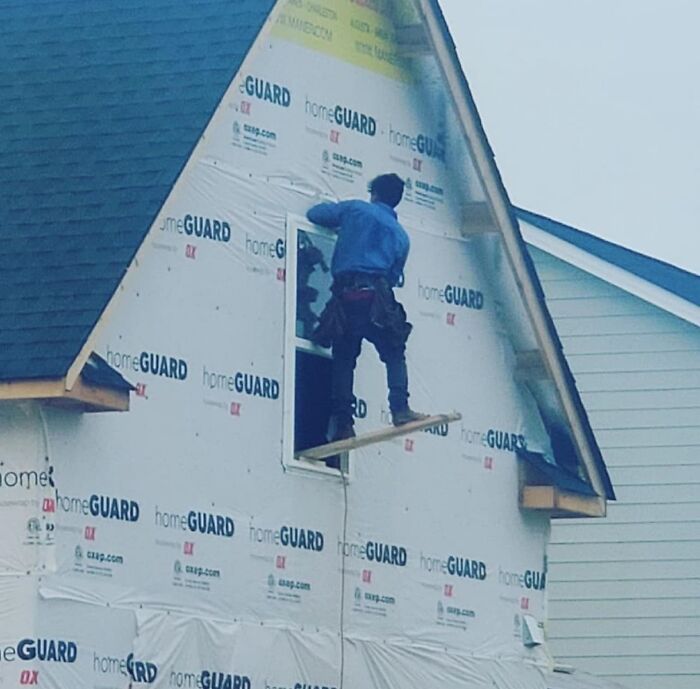 Trabajador en construcción usando tabla insegura en ventana, ejemplo claro de cosas que salieron mal y la gente tuvo que compartir.