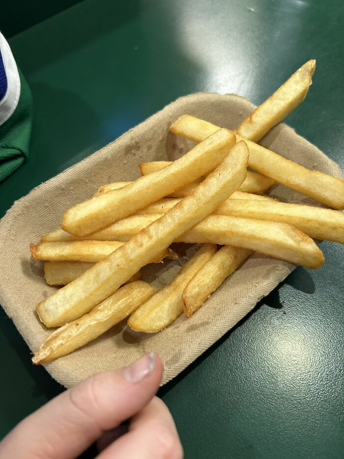 Small portion of French fries in a tray held by a hand, illustrating products getting smaller and more expensive trend.
