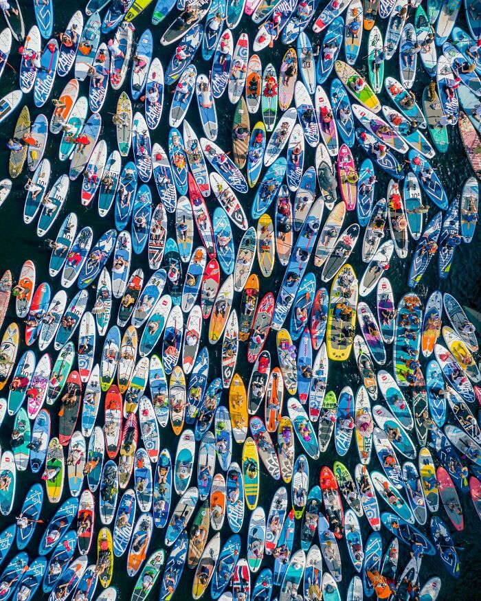 Aerial view of numerous colorful paddleboards with people on water, showcasing stunning aerial photos perspective.