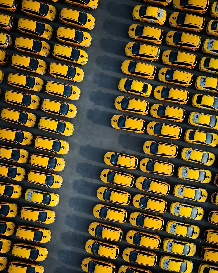 Aerial view of rows of yellow taxis parked closely in a large lot showcasing stunning aerial photography.