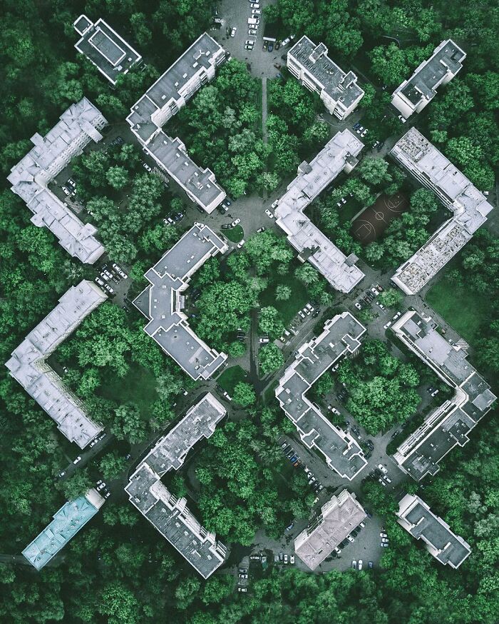 Aerial photo of geometric apartment buildings surrounded by dense green trees showcasing stunning aerial views.