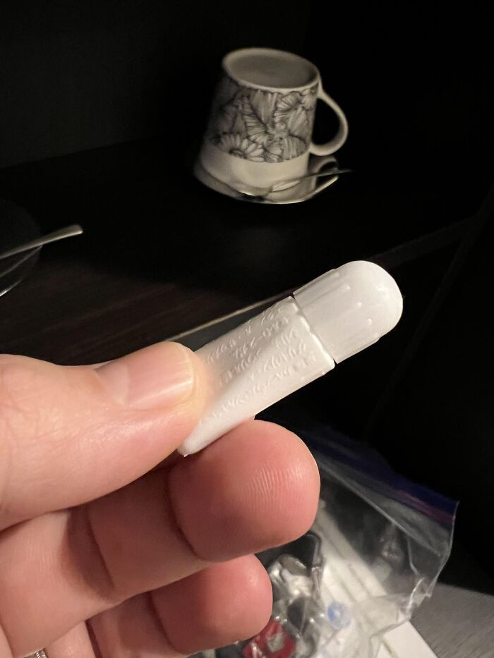 Hand holding an unexpected fail of broken white AirPods case cap, highlighting unfortunate anything gone wrong moment.