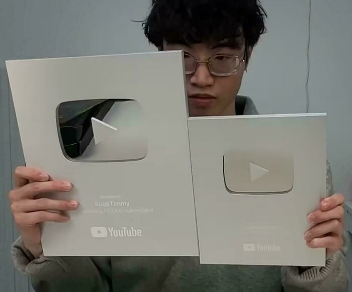 Person holding two different-sized YouTube play button awards, illustrating products getting smaller and more expensive.