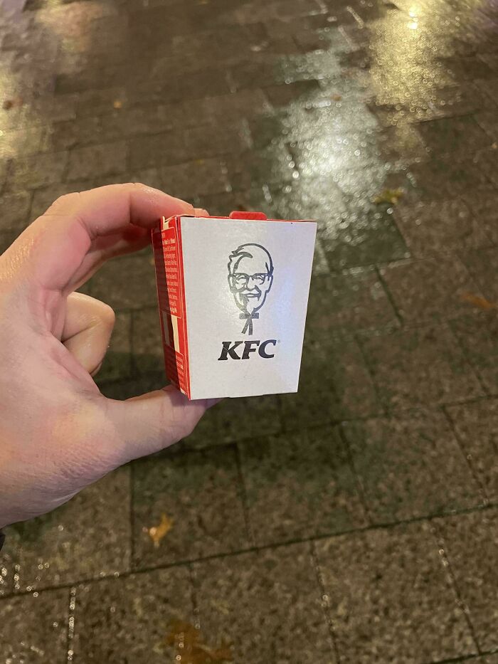 Hand holding a very small KFC product box, illustrating how products are getting smaller and more expensive.