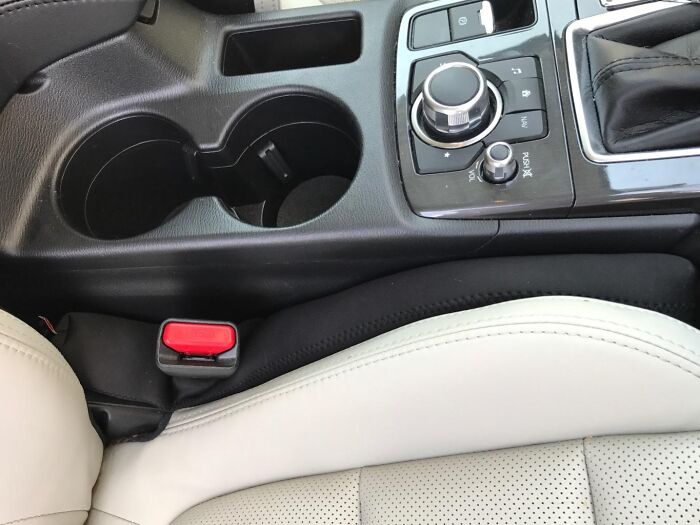 Car center console with cup holders, control knobs, and beige leather seat showcasing Shark Tank pitches hits concept.