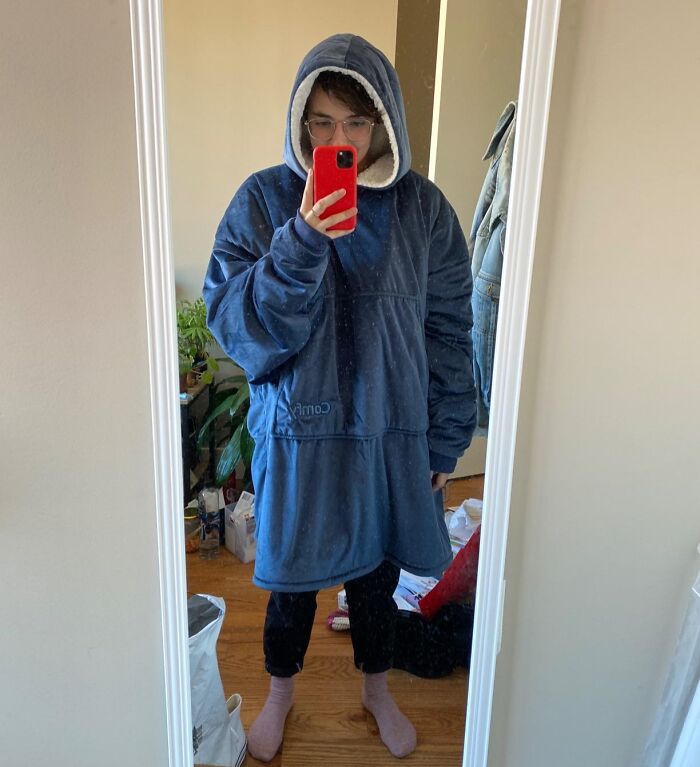 Person wearing a blue cozy oversized hoodie taking a mirror selfie, referencing popular Shark Tank pitches turned massive hits.