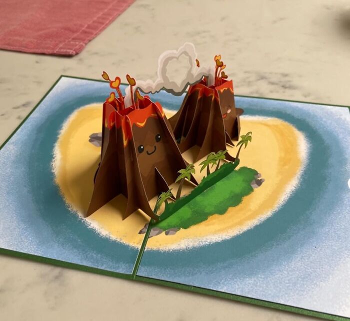 Pop-up volcano card with smiling faces and palm trees, inspired by creative Shark Tank pitches turning into massive hits.