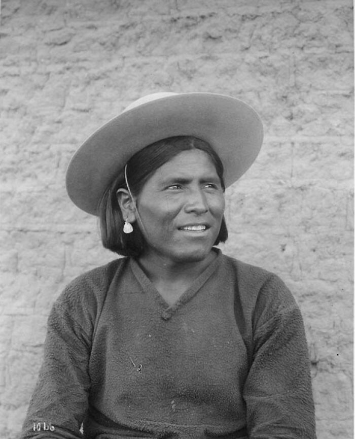 Black and white portrait of a Native American woman wearing a wide-brimmed hat, showing strength and resilience.