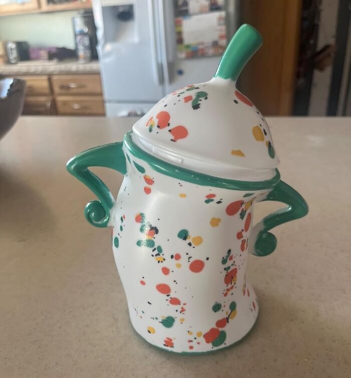 Colorful ceramic kitchen gadget with green handles and lid, featuring a playful splatter design on a white base.