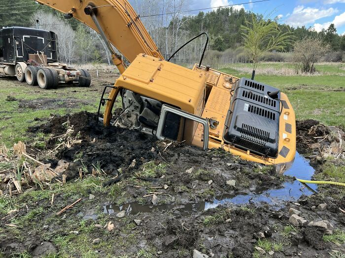 Excavadora atrapada en barro profundo en campo abierto, mostrando una de las cosas que salieron mal y la gente compartió.