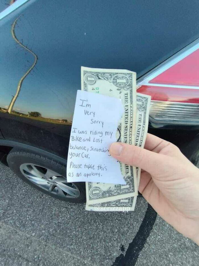 Hand holding an apology note and money for scratching a car, showcasing an unexpected fail in the anything gone wrong group.