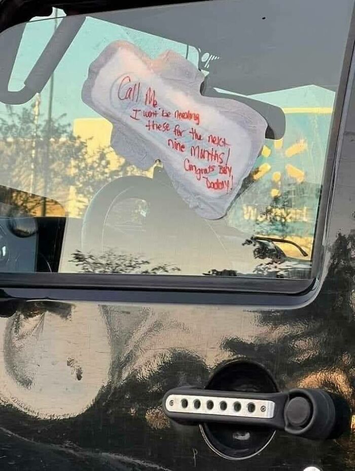 Sanitary pad stuck on a car window with a handwritten message, an unexpected fail caught outdoors.