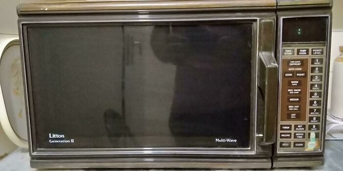 Vintage microwave oven with manual controls and a dark glass door, showcasing how things used to look in kitchen appliances.