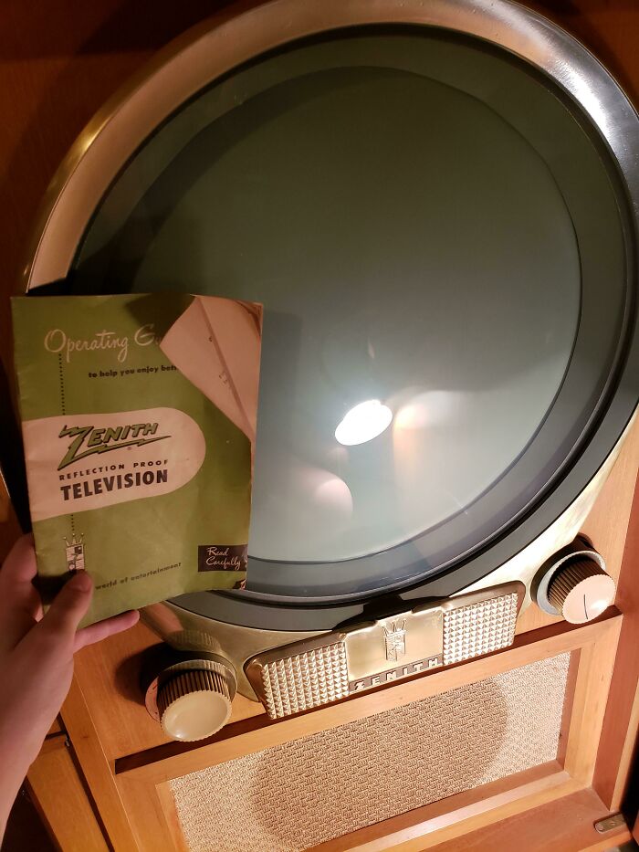 Vintage Zenith television with a round screen and manual knobs, accompanied by an original instruction manual, showing how things used to look.