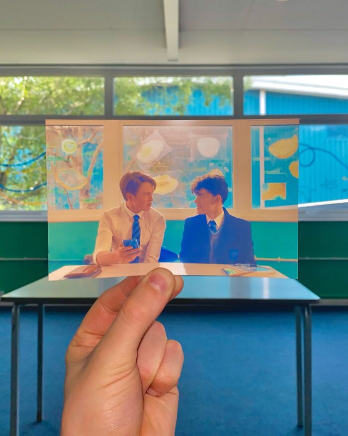 Hand holding a photo comparing real-life filming locations of movie and TV show scenes in a classroom setting.