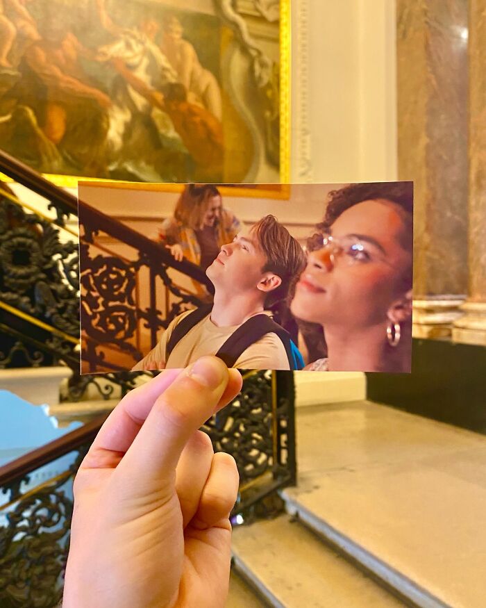 Hand holding a photo from a movie scene matching the real-life filming location of a staircase and ornate railing.